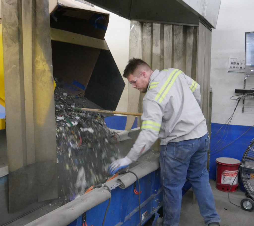 A worker operating a sorting machine at a technology recycling plant.